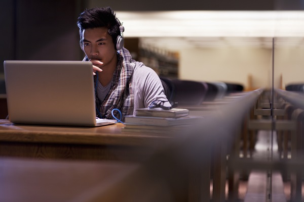 Young man in library at laptop